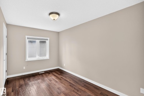 Rich wood-finish flooring, neutral wall tones, and a double-pane window with white blinds - 3329 West Court Nw, Edmonton, AB 