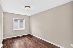 Rich wood-finish flooring, neutral wall tones, and a double-pane window with white blinds - 