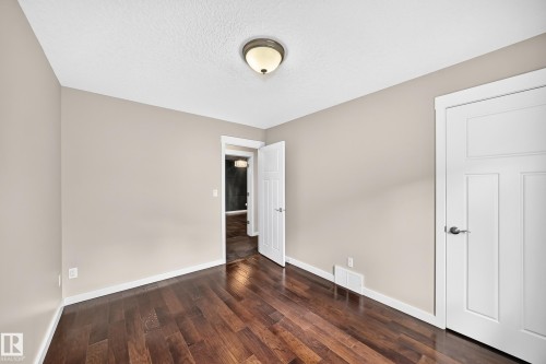 Wood-finish flooring, neutral wall tones, white trim, and a semi-flush ceiling fixture - 3329 West Court Nw, Edmonton, AB 