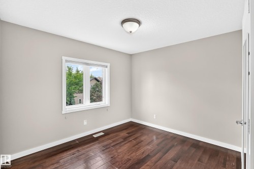 Wood-finish flooring with a neutral wall color, white window trim, and a semi-flush mount ceiling light - 3329 West Court Nw, Edmonton, AB 