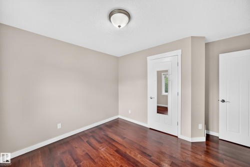 Rich wood-finish flooring, neutral wall tones, white trim, and a contemporary ceiling light fixture - 3329 West Court Nw, Edmonton, AB 