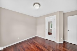 Rich wood-finish flooring, neutral wall tones, white trim, and a contemporary ceiling light fixture - 