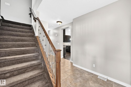 Carpeted staircase with wood handrail and metal balusters - 3329 West Court Nw, Edmonton, AB 