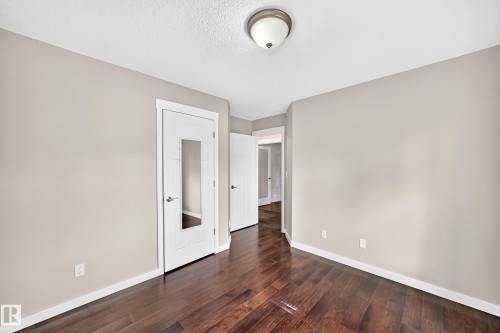 Wood-finish flooring, neutral wall tones, white trim, and a semi-flush mount ceiling light - 3329 West Court Nw, Edmonton, AB 