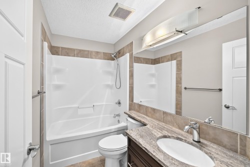 Bathroom featuring a vanity with an undermount sink, stone countertop, and wood-finish cabinetry - 3329 West Court Nw, Edmonton, AB 