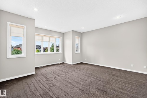 Bright, open room featuring multiple large windows with natural light, neutral wall finishes, and contemporary tile flooring in a geometric pattern - 3329 West Court Nw, Edmonton, AB 
