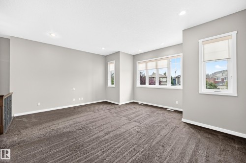 Spacious room featuring neutral carpeting, multiple windows with roller shades, recessed lighting, and light gray wall tones - 3329 West Court Nw, Edmonton, AB 