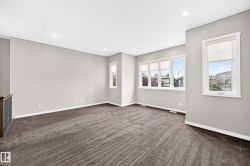 Spacious room featuring neutral carpeting, multiple windows with roller shades, recessed lighting, and light gray wall tones - 