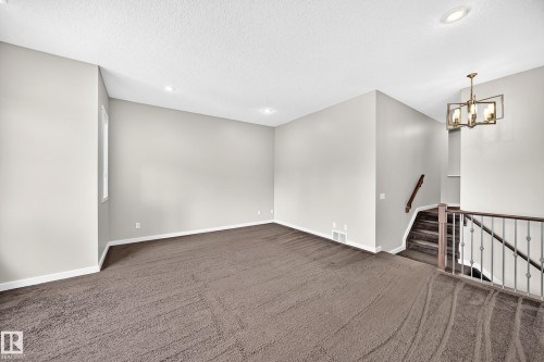 Spacious room with plush carpeting, recessed lighting, and a modern chandelier - 3329 West Court Nw, Edmonton, AB 