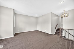 Spacious room with plush carpeting, recessed lighting, and a modern chandelier - 