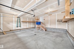Concrete flooring, garage door opener, built-in wooden shelving, and interior access door - 