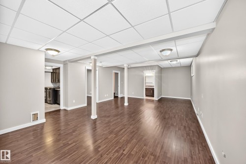 Spacious finished lower level with wood-finish flooring, drop ceiling, recessed lighting, and neutral wall tones - 3329 West Court Nw, Edmonton, AB 