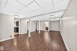 Spacious finished lower level with wood-finish flooring, drop ceiling, recessed lighting, and neutral wall tones - 