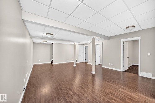Spacious finished room with wood-finish flooring, neutral wall tones, white trim, and recessed panel doors - 3329 West Court Nw, Edmonton, AB 