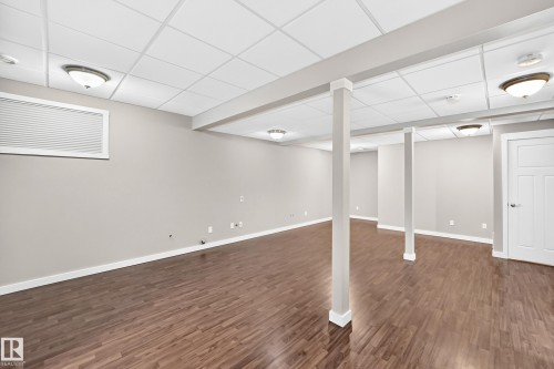 Expansive room featuring wood-finish flooring, neutral wall tones, recessed lighting, and a drop ceiling - 3329 West Court Nw, Edmonton, AB 