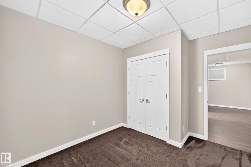 Neutral wall paint, plush carpet flooring, white trim, paneled double doors, and a drop ceiling with recessed lighting - 3329 West Court Nw, Edmonton, AB 