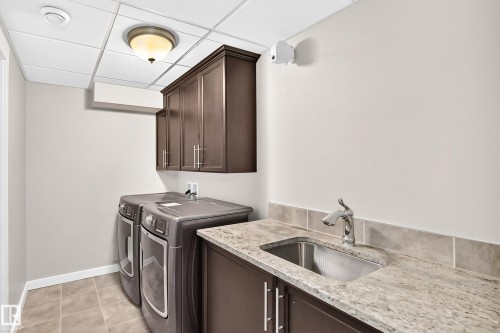 Built-in cabinetry, stainless steel sink, tiled backsplash, and granite-style countertop - 3329 West Court Nw, Edmonton, AB 