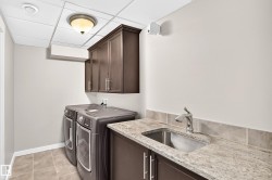 Built-in cabinetry, stainless steel sink, tiled backsplash, and granite-style countertop - 