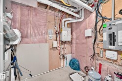 Utility room featuring an electrical panel, water heater, and exposed insulation - 