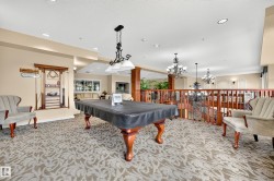 Spacious entertainment area featuring decorative carpet, a billiard table with a dedicated overhead light fixture, and a built-in cue rack - 