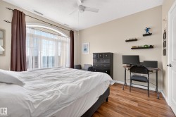 Arched window with gridded panes, ceiling fan, wood-finish flooring, and light-toned walls - 