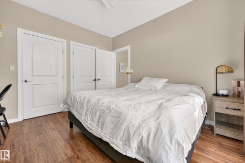 Wood-finish flooring, neutral wall tones, white trim, and white paneled doors - #420 9820 165 St Nw, Edmonton, AB 
