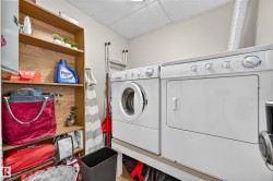 Dedicated laundry area featuring white appliances and wood-finish shelving - 