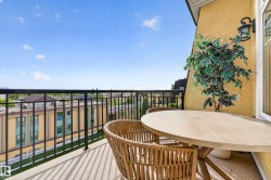 Balcony with black metal railing, stucco exterior, and outdoor wall sconce - 