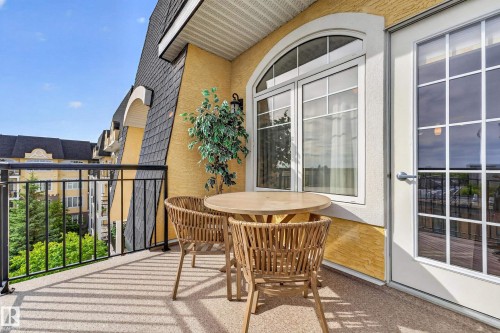Outdoor balcony with textured flooring, black metal railing, and an arched transom window - #420 9820 165 St Nw, Edmonton, AB 