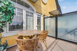 Balcony with textured stucco exterior, arched window, and glass panel railing - 
