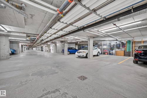 Underground parking garage featuring concrete flooring, structural columns, and overhead lighting - #420 9820 165 St Nw, Edmonton, AB 