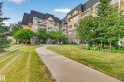 Multi-story residential structure with balconies, a dark pitched roof, and light-toned exterior siding - 