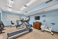 Recreational room featuring multiple fitness machines, light-colored flooring, and recessed fluorescent lighting - 
