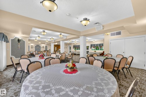 Spacious common area featuring patterned carpeting, recessed lighting, and dual white paneled doors - #420 9820 165 St Nw, Edmonton, AB 