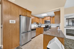 Wood-finish cabinetry, stainless steel appliances, granite-style countertops, tile flooring, and a white subway tile backsplash - 