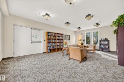 Spacious common area featuring patterned carpeting, multiple flush-mount ceiling lights, and built-in shelving - 