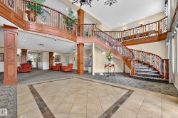 Grand foyer featuring a curved staircase with wood banisters and wrought iron balusters - 
