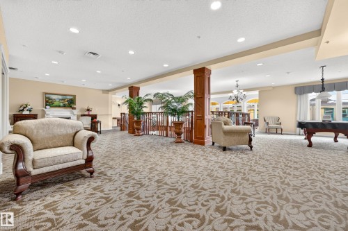 Recessed lighting, patterned carpet flooring, decorative wood columns, wrought iron railing, and a built-in fireplace - #420 9820 165 St Nw, Edmonton, AB 