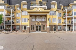 Multi-story building featuring a prominent entry porte-cochère, multiple private balconies with wrought iron railings, and extensive fenestration - 