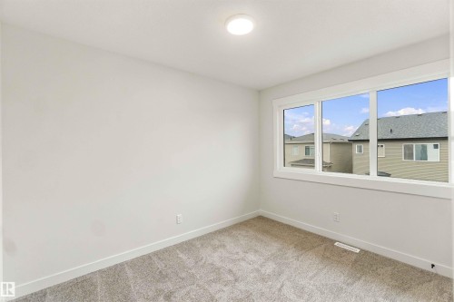 Neutral wall paint, plush carpeting, a large three-panel window, and a ceiling-mounted light fixture - 5852 Raven Crescent Nw, Edmonton, AB 