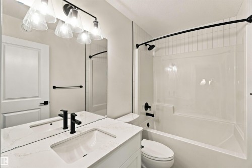 Vanity with quartz countertop and undermount sink, matte black plumbing fixtures, four-light vanity fixture, and full-height mirror - 5852 Raven Crescent Nw, Edmonton, AB 