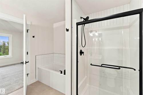 Walk-in shower with black-framed glass enclosure, deep soaking tub with subway tile surround, and matte black fixtures - 5852 Raven Crescent Nw, Edmonton, AB 