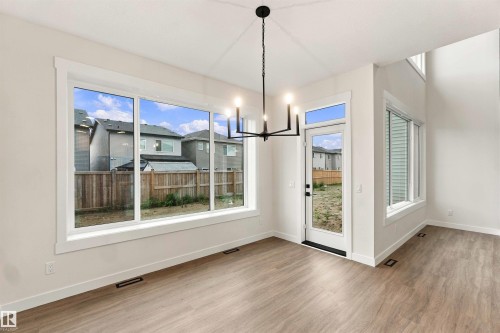 Expansive window wall, wood-finish flooring, high ceilings, contemporary chandelier, and a glass-paneled exterior door - 5852 Raven Crescent Nw, Edmonton, AB 