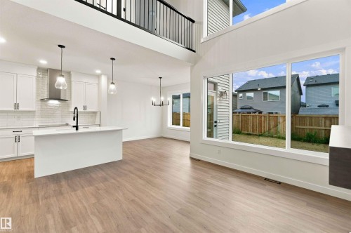 Modern kitchen featuring white cabinetry, a central island, and stainless steel appliances - 5852 Raven Crescent Nw, Edmonton, AB 