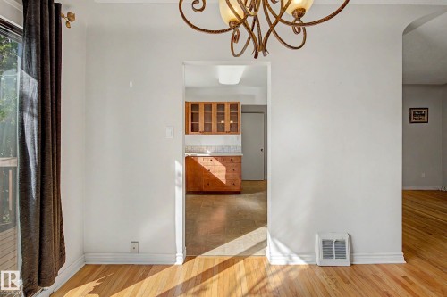 Hardwood flooring, decorative chandelier, sliding glass door, rich wood cabinetry, tile backsplash - 10830 138 Street Nw, Edmonton, AB 