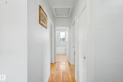 Hallway with wood-finish flooring, white walls, and white trim - 10830 138 Street Nw, Edmonton, AB 