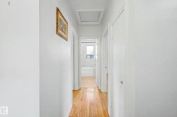 Hallway with wood-finish flooring, white walls, and white trim - 