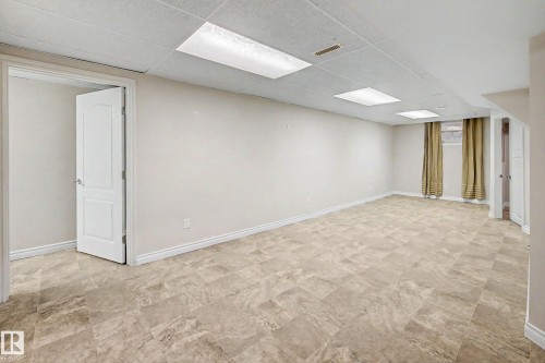 Spacious room featuring neutral wall tones, durable tile flooring, and a drop ceiling with integrated lighting - 10830 138 Street Nw, Edmonton, AB 
