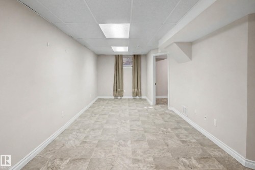 Spacious room featuring light-colored flooring, neutral wall paint, and recessed ceiling lighting - 10830 138 Street Nw, Edmonton, AB 