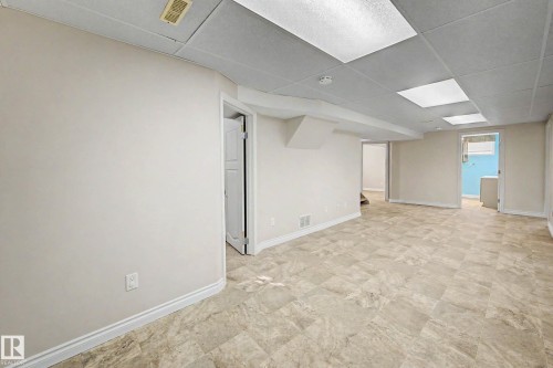 Spacious room featuring neutral tone walls, tile-look flooring, and a drop ceiling with recessed lighting - 10830 138 Street Nw, Edmonton, AB 
